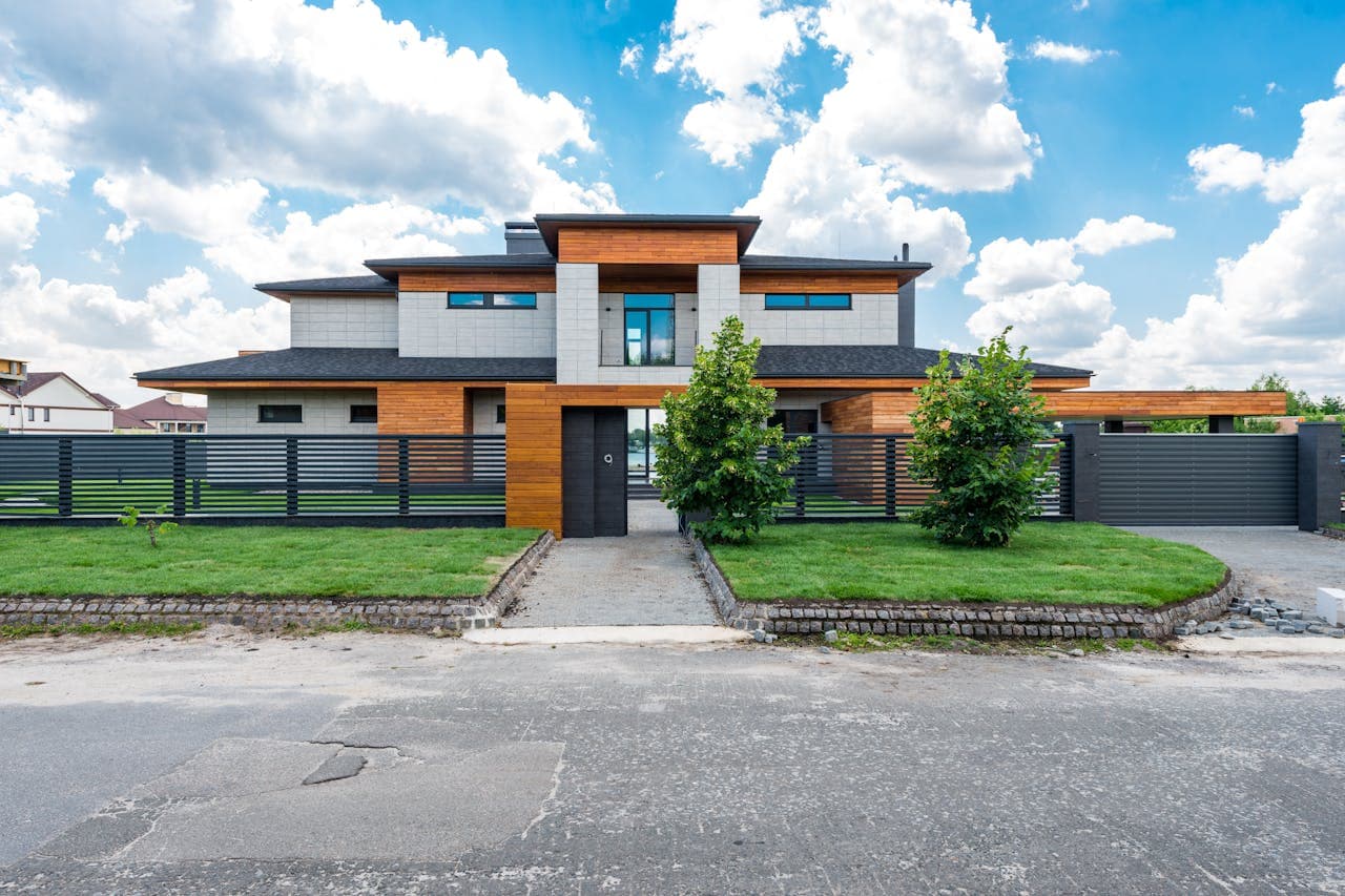 Villa moderne avec clôture à lames horizontales anthracite et portail coulissant automatique sur allée pavée