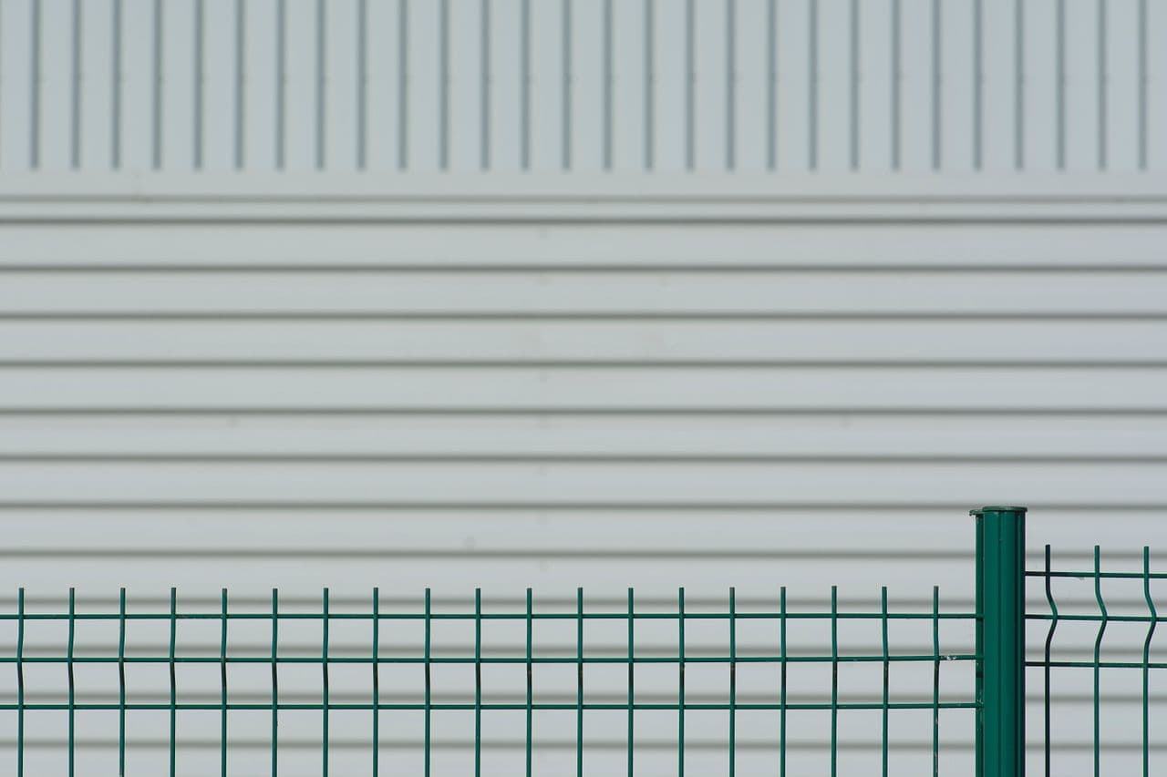 Panneau de grillage rigide vert soudé avec poteau rond vert — vue minimaliste sur fond blanc
