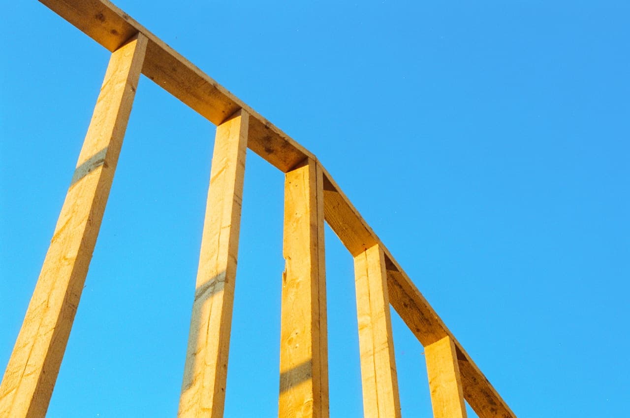 Montants en bois d'une ossature de cloison en construction vus de dessous sur fond de ciel bleu