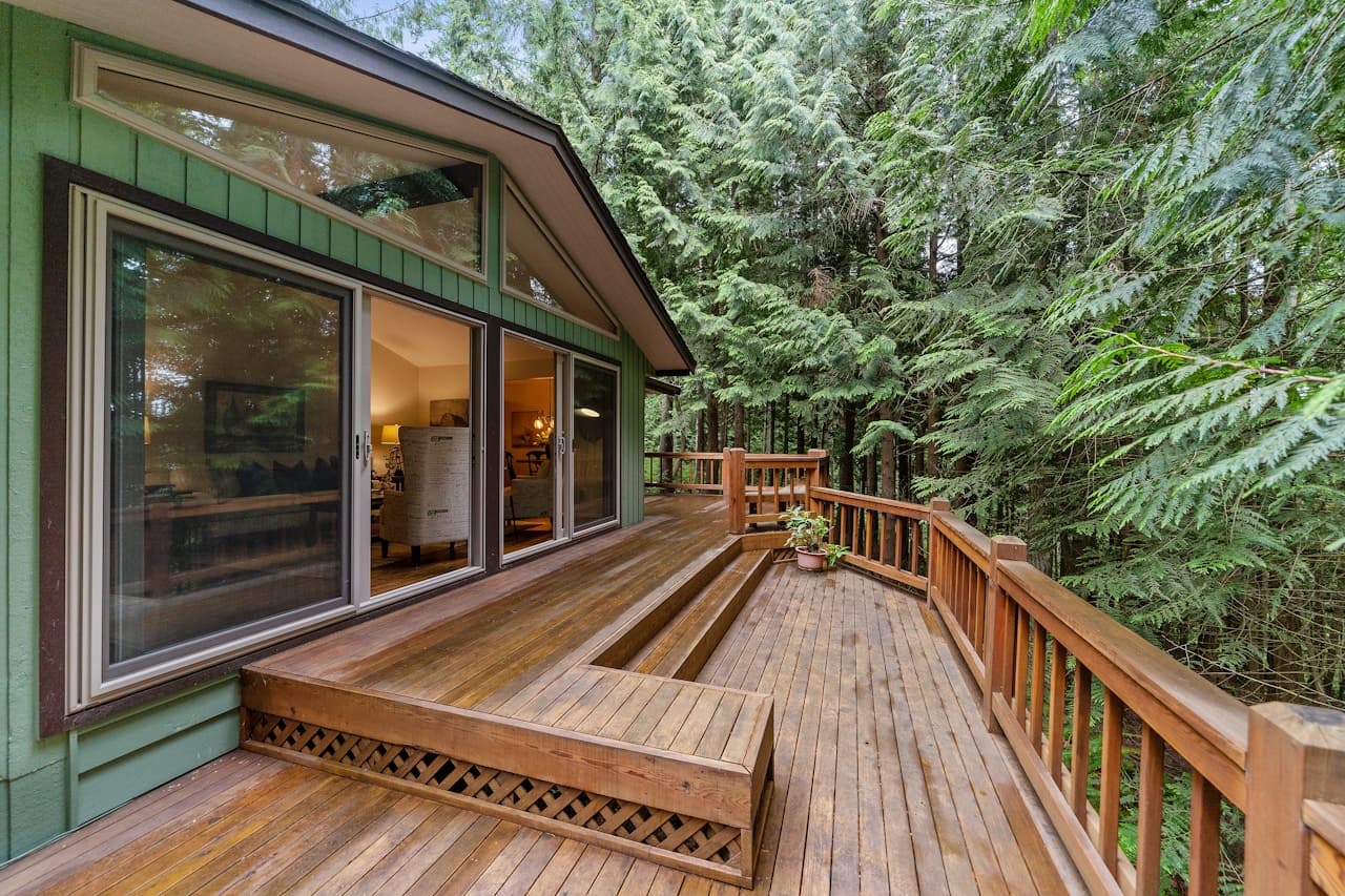 Terrasse en bois naturel devant une porte-fenêtre, vue extérieure ensoleillée